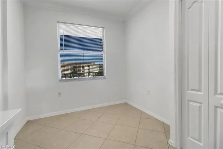 Tiled empty room with ornamental molding and a wealth of natural light