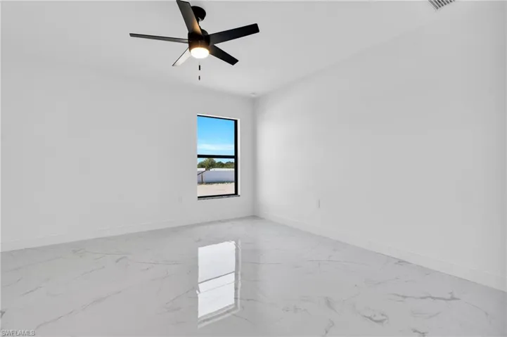 Empty room featuring light marble finish floors and ceiling fan
