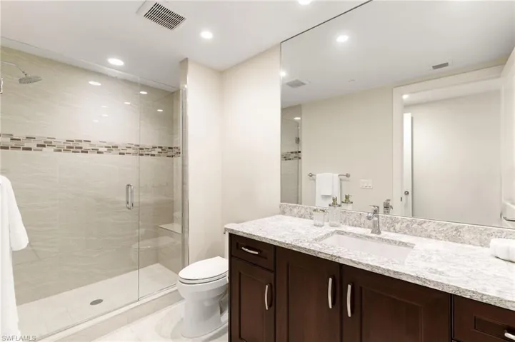 Additional full Bath with an enclosed walk-in shower, vanity, tile patterned floors, and toilet