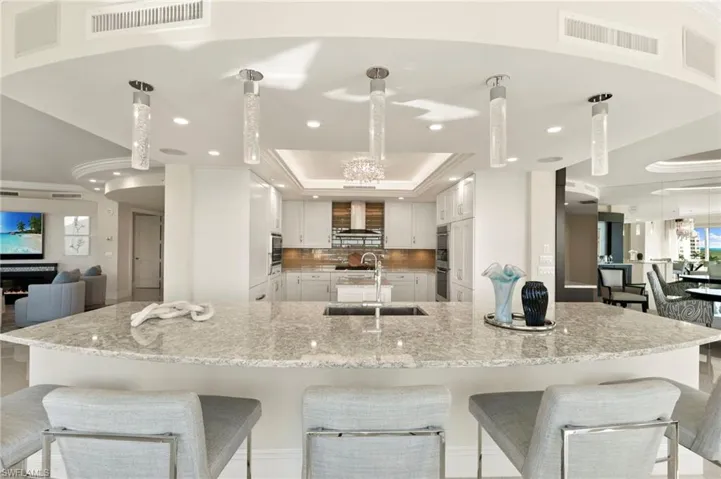 Kitchen featuring sink, custom cabinetry, smicrowave, pendant lighting, and light Quartz countertops