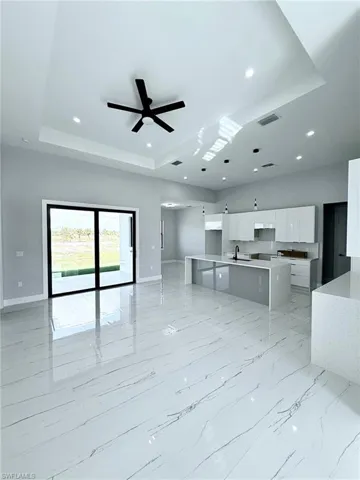 Kitchen featuring white cabinetry, a large island, a raised ceiling, hanging light fixtures, and ceiling fan