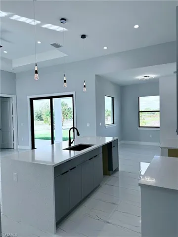 Kitchen with gray cabinets, sink, pendant lighting, and a wealth of natural light