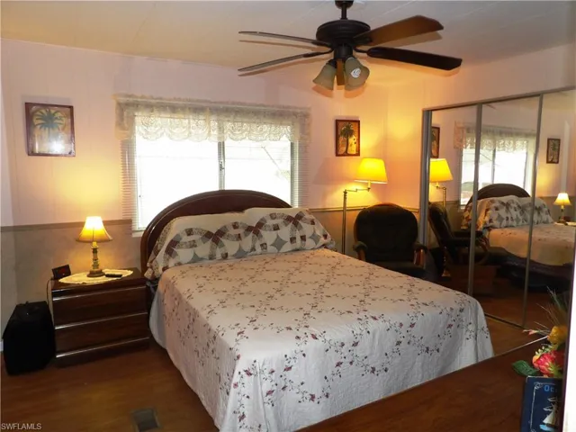 Bedroom with dark wood-type flooring, ceiling fan, and a closet