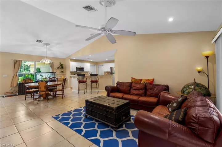 Living area with light tile patterned floors, vaulted ceiling, and a ceiling fan
