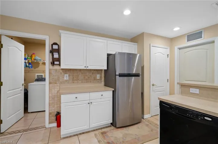 Kitchen with washer / clothes dryer, freestanding refrigerator, dishwasher, light countertops, and decorative backsplash