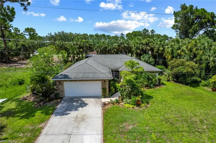 Ranch-style house featuring a garage, concrete driveway, a forest view, and a shingled roof