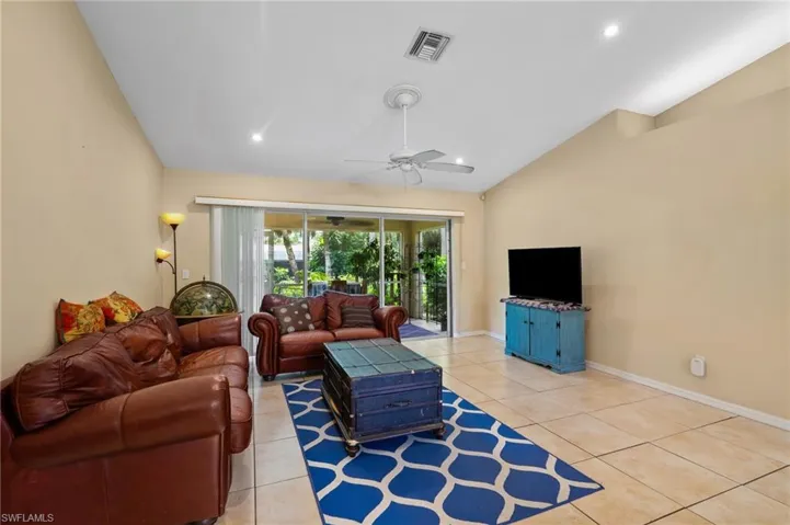 Living area featuring lofted ceiling, ceiling fan, light tile patterned flooring, and recessed lighting