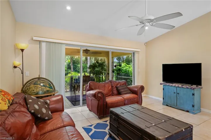 Living room with light tile patterned floors, a ceiling fan, and vaulted ceiling
