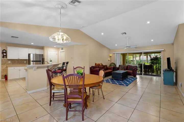 Dining space featuring light tile patterned flooring, vaulted ceiling, ceiling fan, and recessed lighting