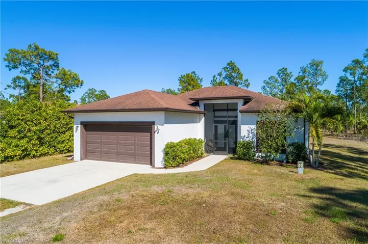 Prairie-style house with stucco siding, an attached garage, a front lawn, and concrete driveway