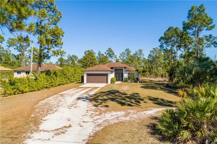 View of front of property with driveway, a front lawn, a garage, and stucco siding