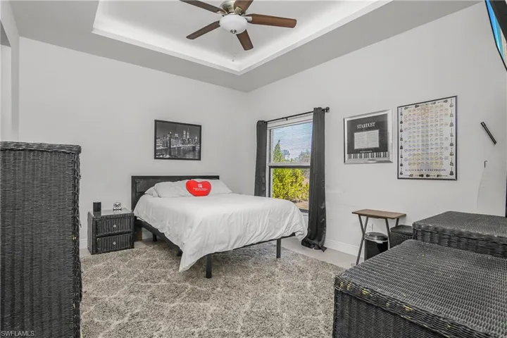 Carpeted bedroom with a tray ceiling and ceiling fan