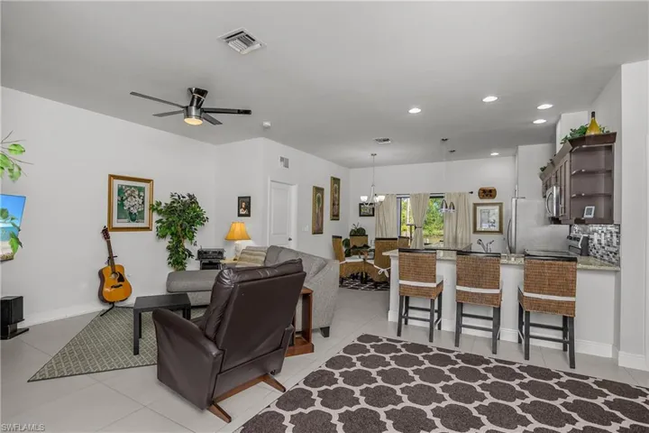 Living room featuring a ceiling fan, suspended lighting, and light tile patterned flooring