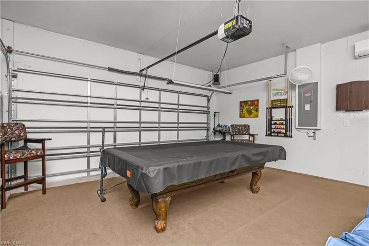 Recreation room with a garage, electric panel, billiards table, and light colored carpet