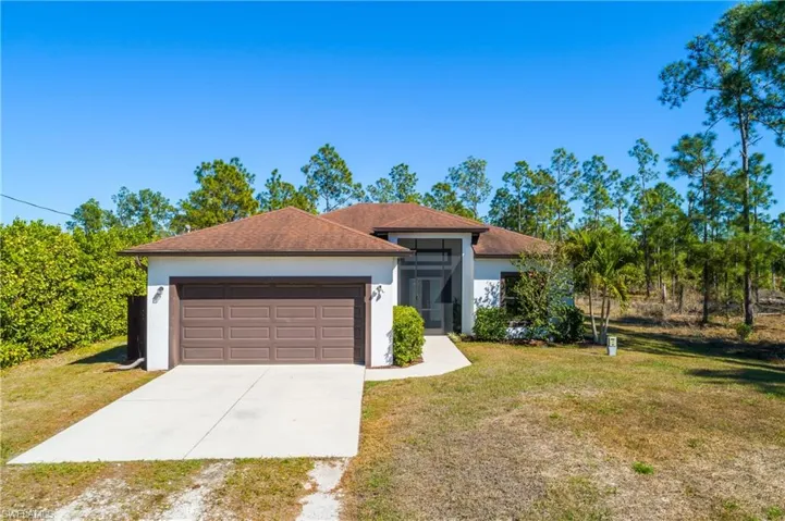 View of front of home with driveway, a front yard, stucco siding, and an attached garage