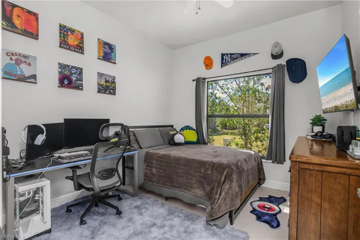 Bedroom featuring an office area, ceiling fan, and light carpet