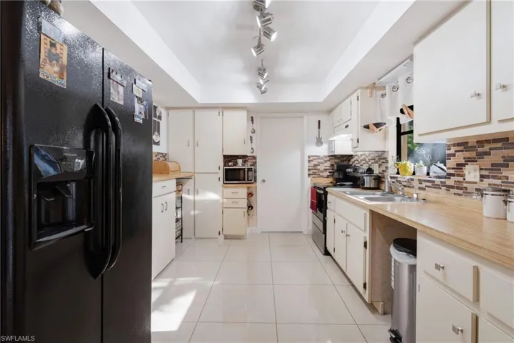 Kitchen with rail lighting, light tile patterned floors, stainless steel appliances, a raised ceiling, and sink