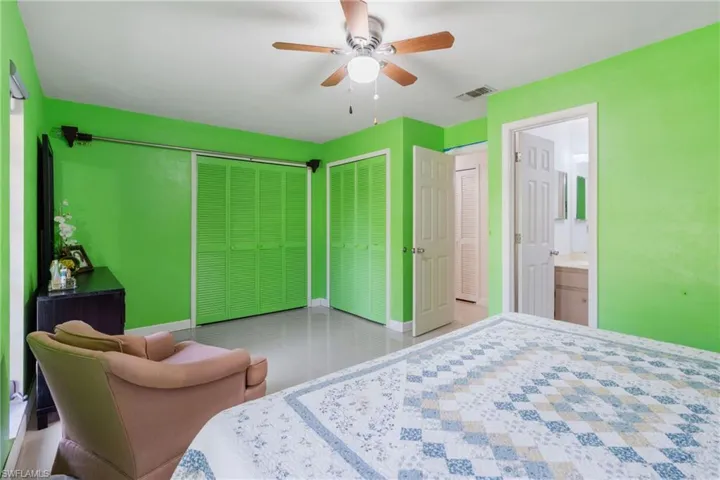 Bedroom featuring two closets, ceiling fan, connected bathroom, and light tile patterned floors