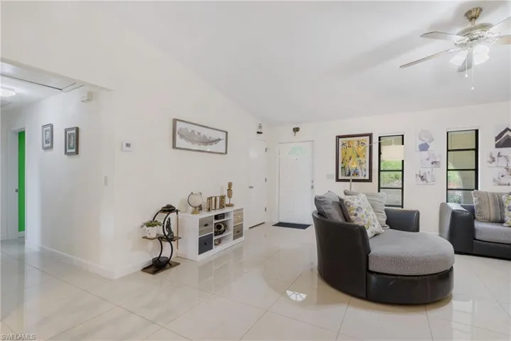 Tiled living room featuring ceiling fan and lofted ceiling