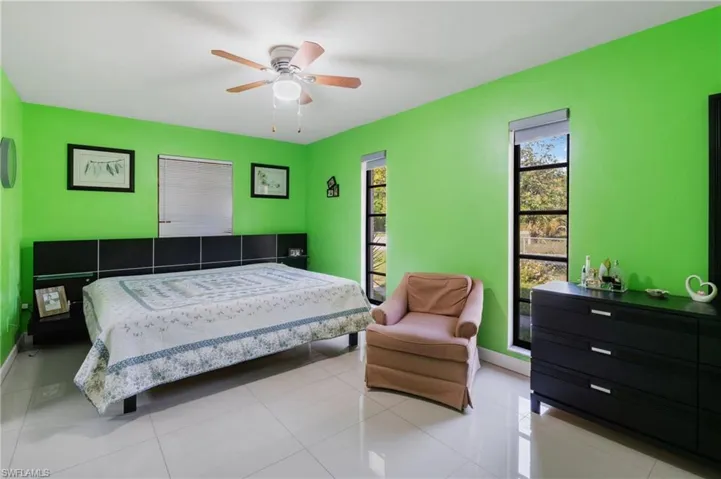 Bedroom with light tile patterned flooring, multiple windows, and ceiling fan