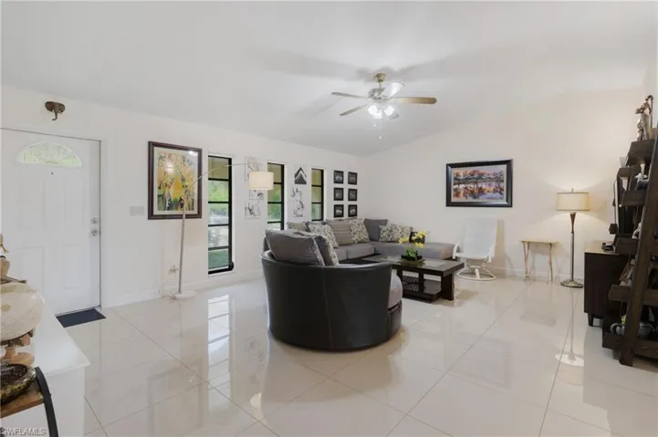 Living room featuring light tile patterned flooring, ceiling fan, and vaulted ceiling