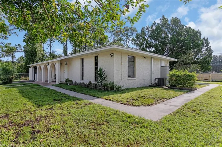 View of property exterior with central AC, a garage, and a lawn