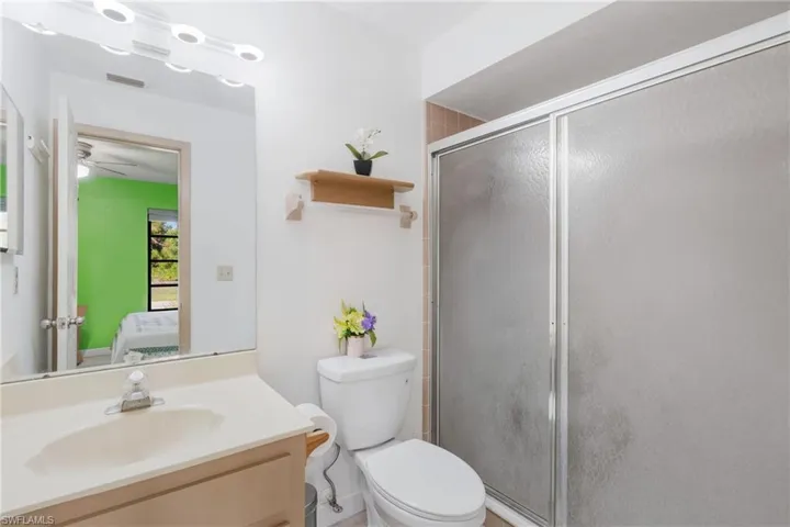 Bathroom with an enclosed shower, toilet, vanity, and ceiling fan