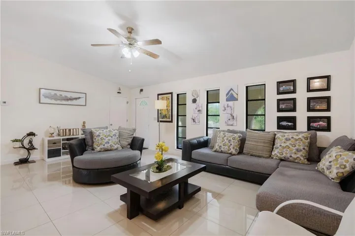 Tiled living room featuring ceiling fan and vaulted ceiling