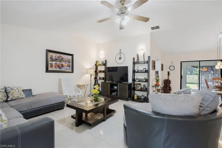 Tiled living room with ceiling fan and vaulted ceiling