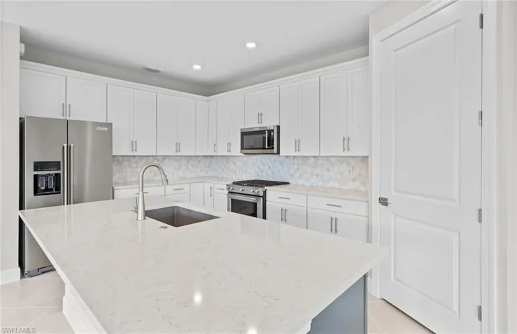 Kitchen featuring white cabinets, a kitchen island with sink, high quality appliances, and sink