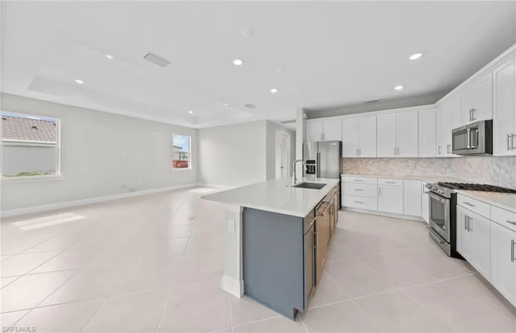 Kitchen featuring stainless steel appliances, white cabinets, and a wealth of natural light