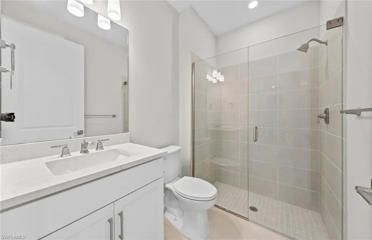 Bathroom featuring walk in shower, vanity, toilet, and tile patterned floors