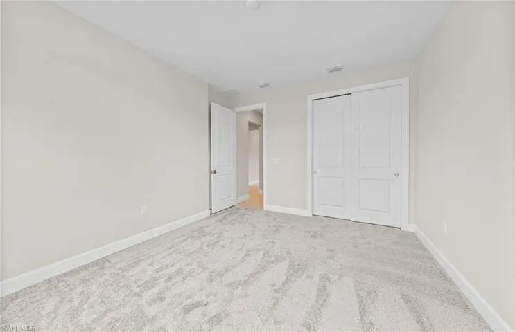 Unfurnished bedroom featuring light carpet and a closet
