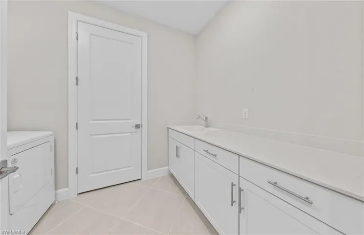 Bathroom featuring separate washer and dryer, tile patterned flooring, and vanity