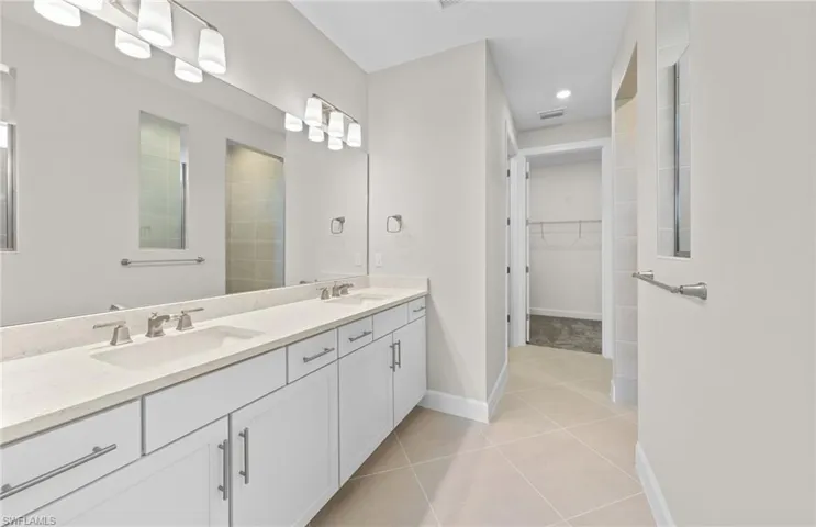 Bathroom featuring a tile shower, tile patterned flooring, and vanity