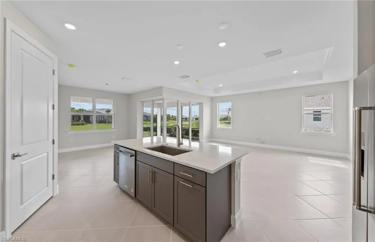Kitchen with a tray ceiling, sink, stainless steel appliances, and plenty of natural light