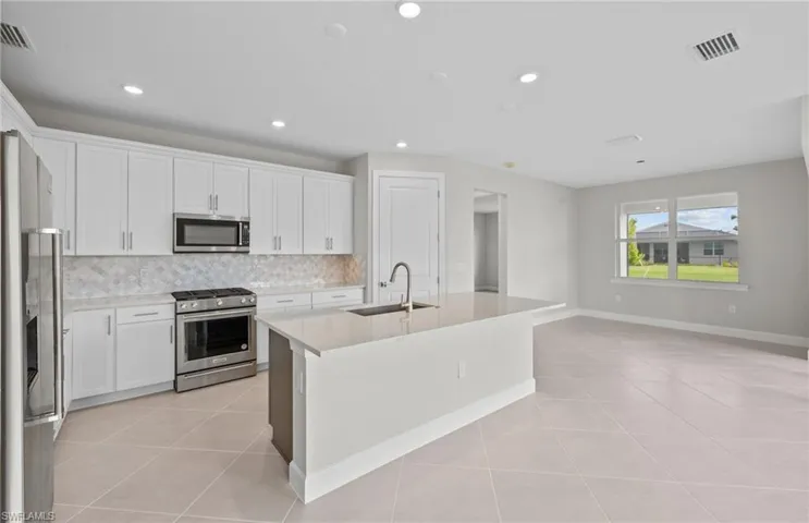 Kitchen featuring an island with sink, white cabinetry, sink, and stainless steel appliances