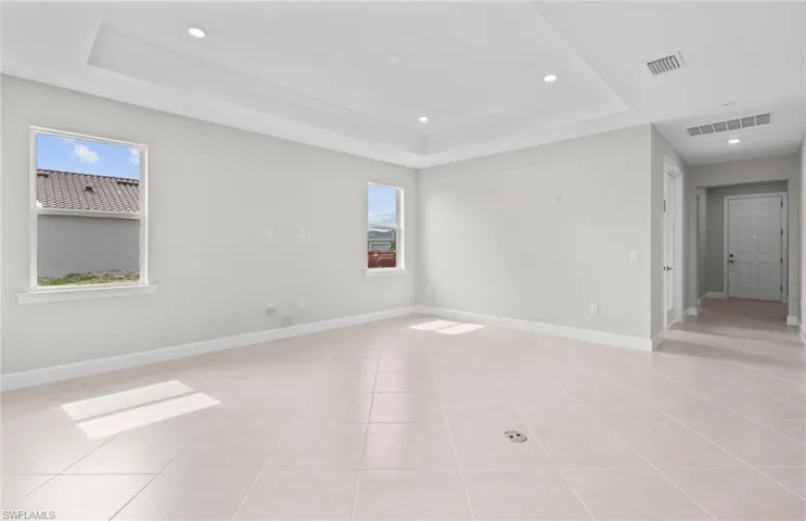 Empty room featuring a raised ceiling and light tile patterned floors