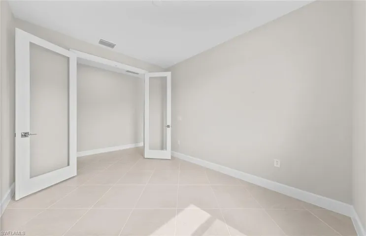 Unfurnished den with french doors and light tile patterned flooring