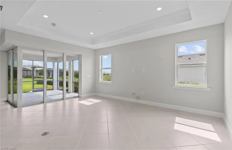 Empty room with a raised ceiling, crown molding, and a wealth of natural light
