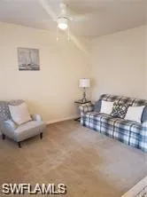 Carpeted living area featuring a ceiling fan