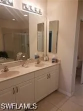 Bathroom with double vanity, light tile patterned flooring, and a stall shower