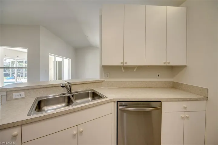 Kitchen featuring dishwasher, a peninsula, light countertops, and white cabinets
