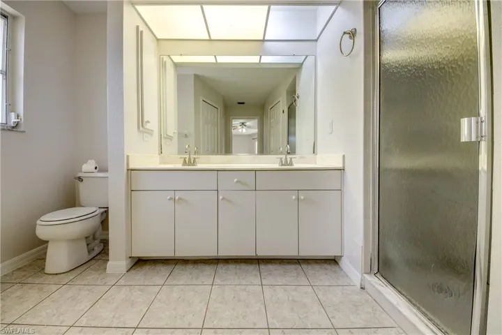 Full bath featuring double vanity, a shower stall, and light tile patterned flooring