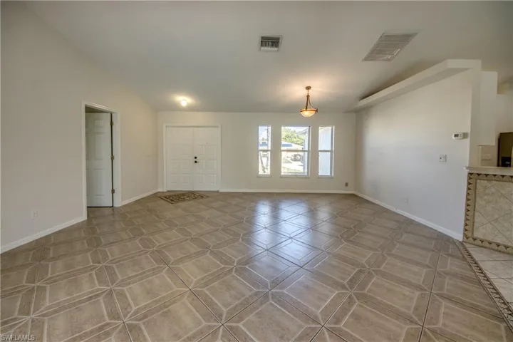 Unfurnished living room featuring vaulted ceiling and baseboards