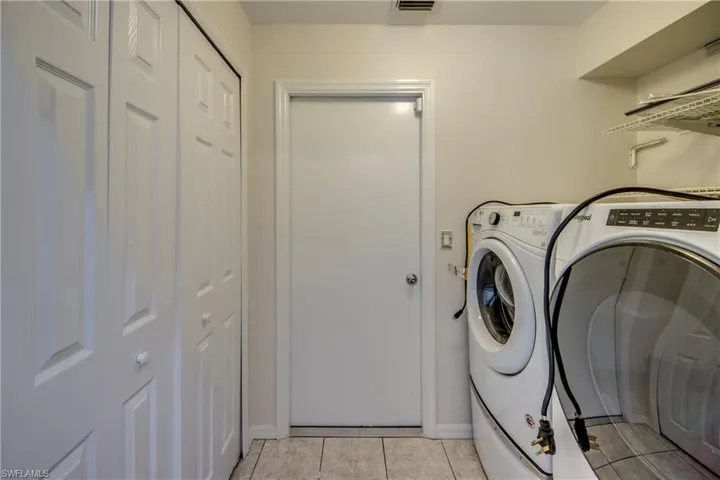 Laundry room with independent washer and dryer and light tile patterned floors