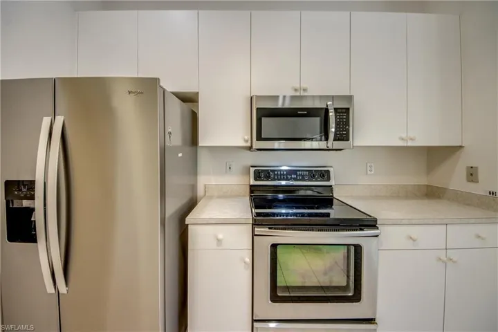 Kitchen with stainless steel appliances, light countertops, and white cabinets