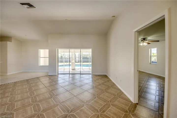 Empty room with lofted ceiling, ceiling fan, and light tile patterned floors