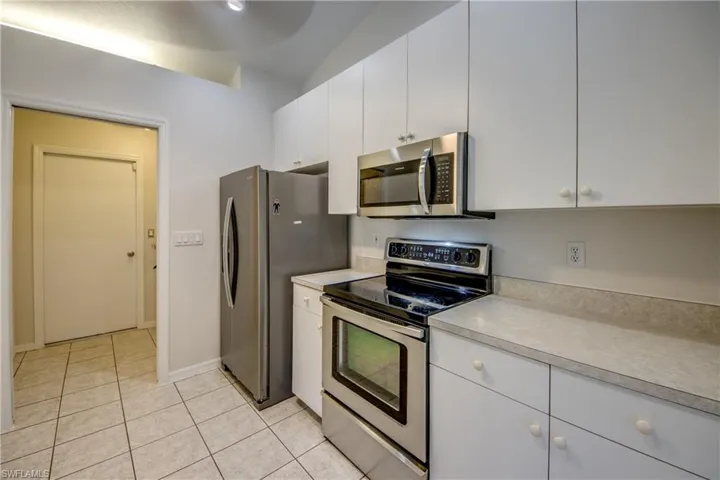 Kitchen featuring stainless steel appliances, white cabinetry, light countertops, and light tile patterned floors