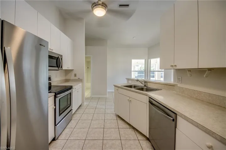 Kitchen featuring stainless steel appliances, a peninsula, and white cabinetry